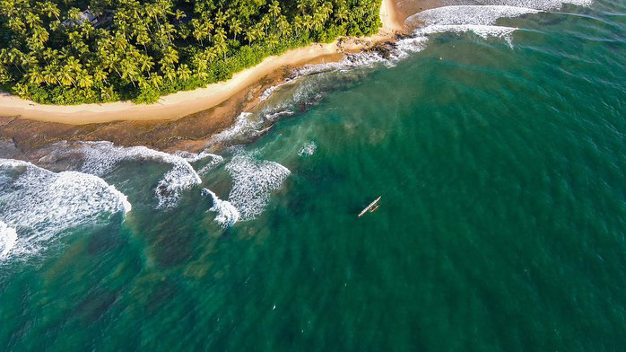 Vista aérea da canoa solitária próxima à praia de coqueiros